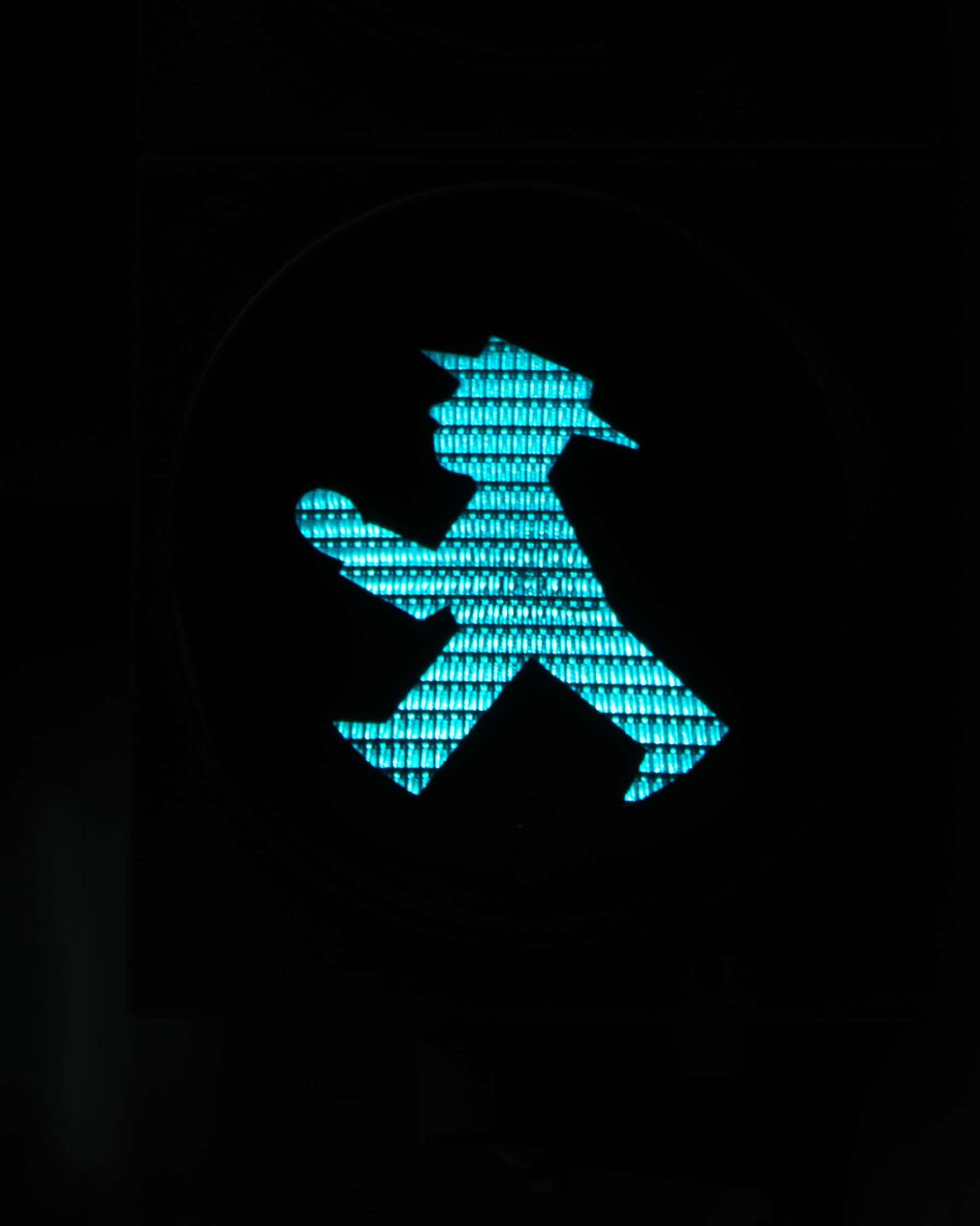 The green Ampelmann: a long stride, hat tilted, walk.